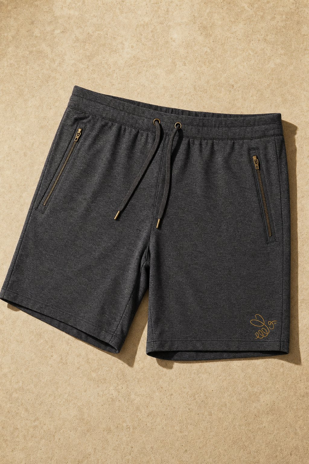 The Short in Graphite Heather, flatlay on warm sandstone.